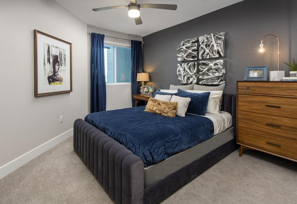 Luxury One-Bedroom Apartments in Irvine, CA - The Royce - Bedroom with Wall-to-Wall Carpeting, Grey Accent Wall, and Modern Decor